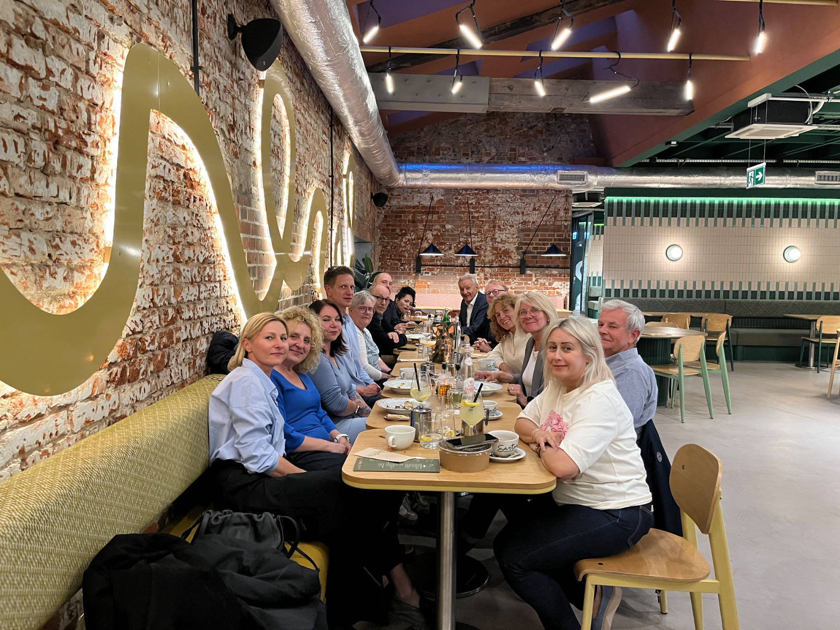 Primotex team members seated along a long table at a restaurant in Łódź, smiling towards the camera